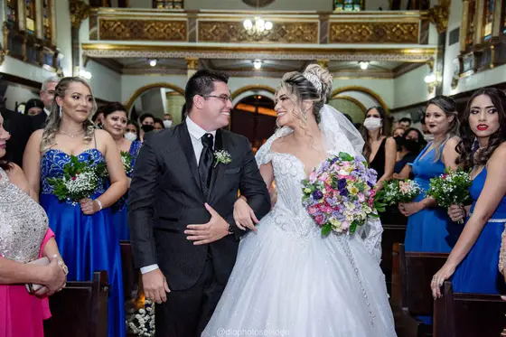 Noivos saindo da igreja de braços dados, entre os padrinhos