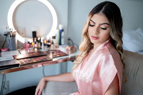 Debutante de robe rosa diante do espelho de maquiagem